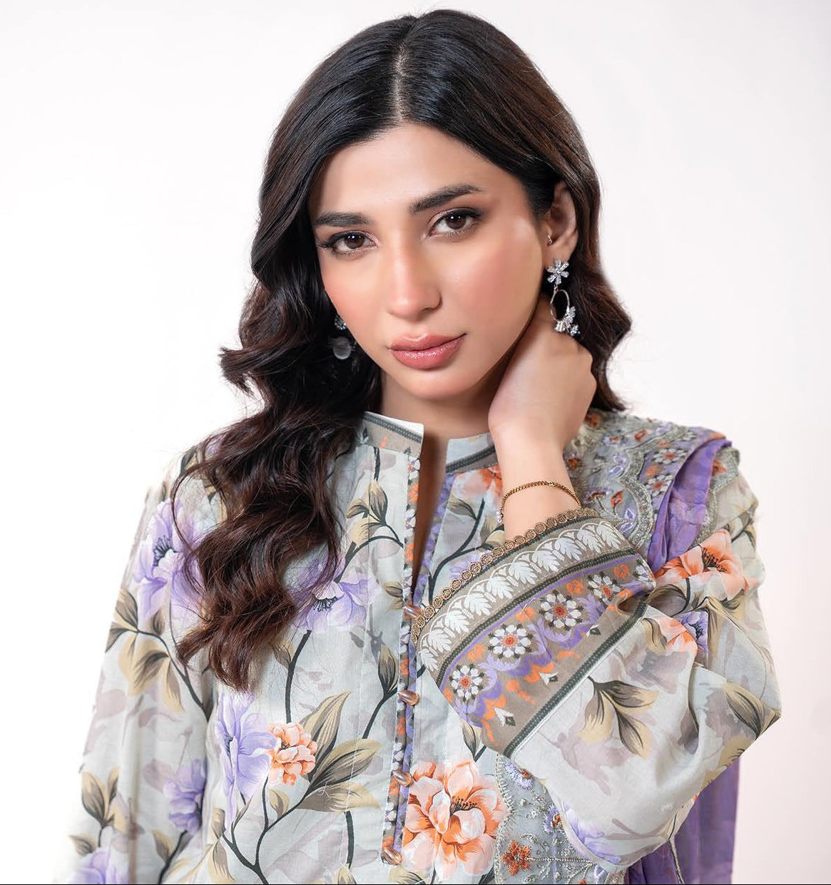Woman wearing a floral embroidered outfit with a white background