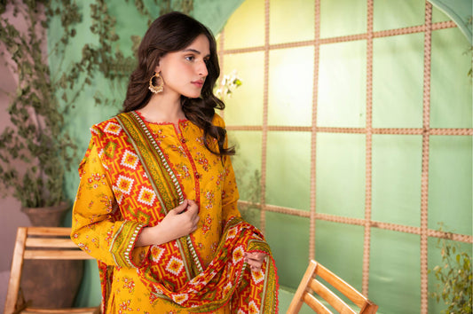 Woman in a yellow and orange traditional outfit with a patterned scarf, sitting on a wooden chair.