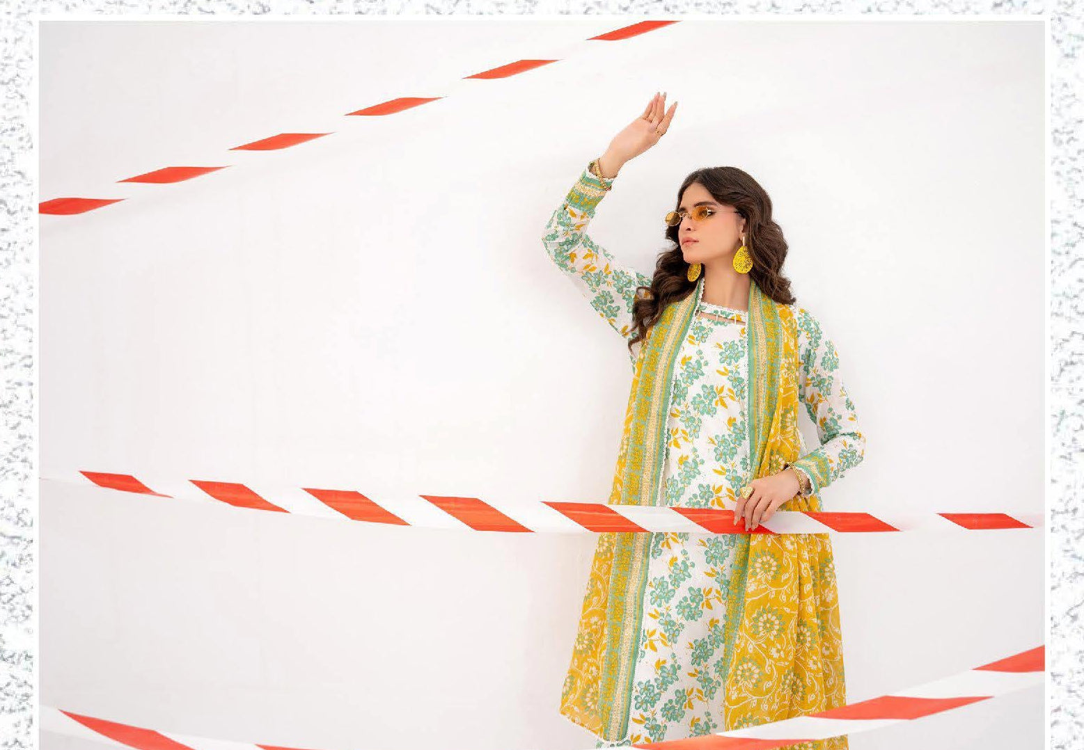 Woman in a yellow and green traditional outfit posing against a white background with red and black striped elements.