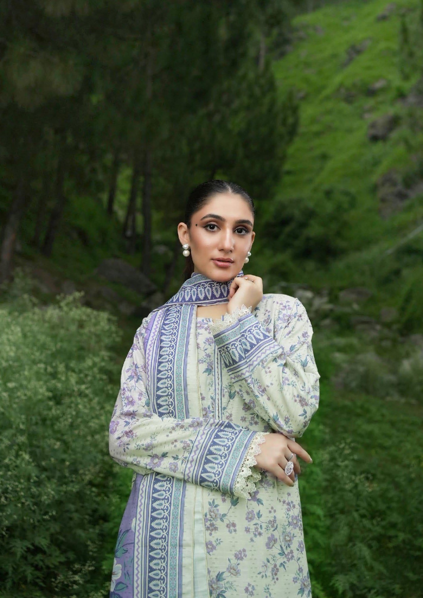 Woman in a patterned outfit standing in a green outdoor setting