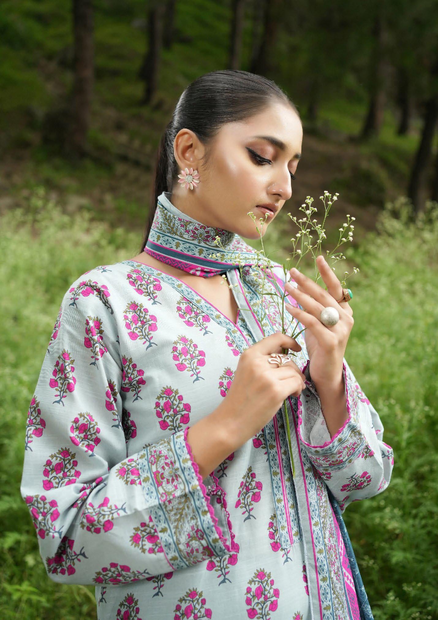 Woman in a floral dress holding a flower in a natural setting