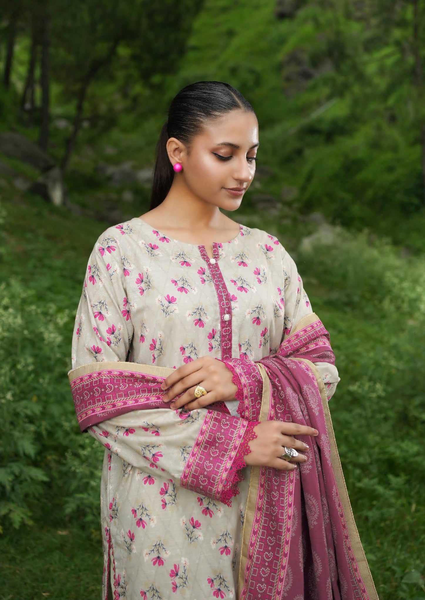 Woman in a floral outfit with a pink dupatta standing outdoors.